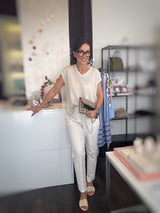 Offwhite Hose kombiniert mit Lurex Shirt von Absolut Cashmere -auch in Offwhite und beigefarbene Pantoletten. In der Hand eine Pochette in Schwarz-Beige von Sorena.