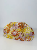 Bucket Bag mit abnehmbarer goldenen Schulterkette. Die Tasche ist in einem gesprenkelte Blumenmuster in den Farben Gelb, Flieder, Rostrot. Die Tasche ist zum aufklappen und kann auch als Kulturbeutel genutzt werden.