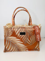 Große rechteckige Tote‑Bag in Rostrot‑Beige mit gold‑beigem Palmblatt‑Muster aus gewebtem, texturiertem Stoff. Oben Fransenkante, zwei kurze Stoffgriffe, Reißverschluss, rotes Velvet‑Innenfutter, abnehmbare Logo‑Schulterriemen, Maße ca. 42 × 30 × 15 cm