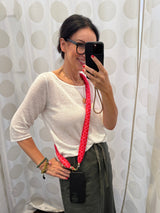 Crossbody Handykette in Pink und roten Herzen gezeigt von einer Frau in einem weissen Sweater und olivegrünem Rock.