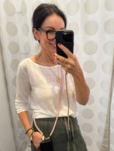 Rosafarbene Crossbody Handykette aus Acryl gezeigt auf einer Frau mit weissem Sweater und olivgrünem Rock.