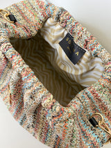 Geöffnete Bucket Bag mit Blick auf das Innenfutter im Zebra Design. Die Bucket Bag hat eine abnehmbare goldenen Schulterkette. Die Tasche ist in einem vertikalen Strickmuster in zarten Farbtönen Gelb, Hellblau, Rostrot, Grün, Schwarz, Beige. Die Tasche ist zum aufklappen und kann auch als Kulturbeutel genutzt werden.