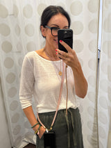 Rosafarbene Crossbody Handykette aus Acryl gezeigt auf einer Frau mit weissem Sweater und olivgrünem Rock.