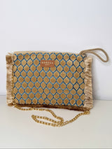 Beige-goldene Clutch mit geometrischem Muster aus samtigen Fransen-Tupfen auf hellblauem Grund. Die Tasche hat einen goldfarbenen Reißverschluss mit Quaste, eine kleine Label-Plakette mit „SORENA“, und eine feine Fransenbordüre; innen goldfarben gefüttert. Eine abnehmbare, goldfarbene Kette sorgt dafür, dass man die Tasche auch als Schultertasche tragen kann. Die Kordelschlaufe sorgt dafür, dass man die Tasche auch in der Hand tragen kann.