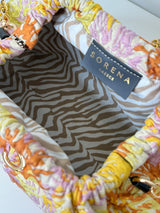 Detailaufnahme in offenem Zustand der Bucket Bag. Man sieht das Innenleben im Zebra Print und das Label "Sorene Greece". Die Bucket Bag mit abnehmbarer goldenen Schulterkette. Die Tasche ist in einem gesprenkelte Blumenmuster in den Farben Gelb, Flieder, Rostrot. Die Tasche ist zum aufklappen und kann auch als Kulturbeutel genutzt werden.an