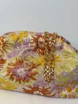 Bucket Bag mit abnehmbarer goldenen Schulterkette. Die Tasche ist in einem gesprenkelte Blumenmuster in den Farben Gelb, Flieder, Rostrot. Die Tasche ist zum aufklappen und kann auch als Kulturbeutel genutzt werden.